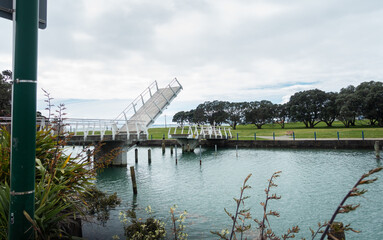 Bascule pedestrian bridge lifting to let boats pass through at Milford Beach Reserve. Auckland.