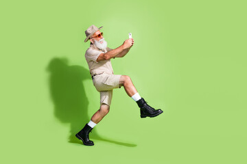Photo of traveler senior man step walk have trip using phone for gps navigation isolated green...