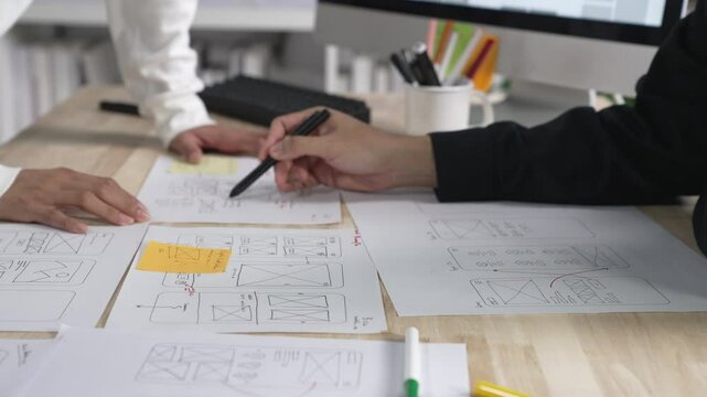 UX UI designers discussing and brainstorming on wireframes for a website and mobile app prototype, in the concept of website and mobile application design concept.