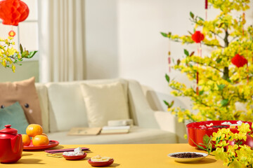 A frontal view of a vivid living room adorned for Tet, along with a jam tray, tangerines, melon seeds, lucky envelopes, and yellow apricot trees, is featured in this still life image of the Tet idea.