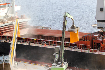 Loading of corn into the ship's hold at the same time by a mobile conveyor and a grab manipulator