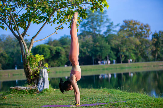Young woman practicing yoga on soft green grass beside the lake. Young woman practicing yoga in nature. Healthy lifestyle. Concept of vitality, balance, mindfulness, Zen energy, calmness, relaxation, 