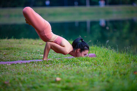 Young woman practicing yoga on soft green grass beside the lake. Young woman practicing yoga in nature. Healthy lifestyle. Concept of vitality, balance, mindfulness, Zen energy, calmness, relaxation, 