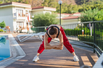 Young woman doing warm up or stretching exercises in swimming pool area of ​​residential building 