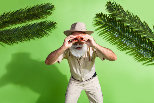 Photo of adventurer senior man watch binoculars glasses observe wildlife tropics isolated green color background - Powered by Adobe