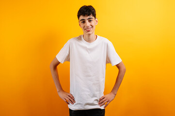 Smiling teen boy in white t-shirt, yellow background.