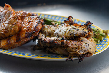 Grilled meat, chicken and pork and grilled green asparagus on a blue and yellow plate