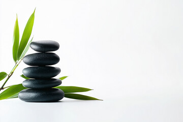 Obraz premium a stack of black rocks and bamboo leaves on a white background