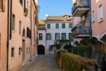 Typical Italian narrow street in old town Treviso in warm autumn days. Colourful buildings. Tourist destination. 