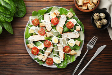 Delicious Caesar salad with chicken served on wooden table, flat lay