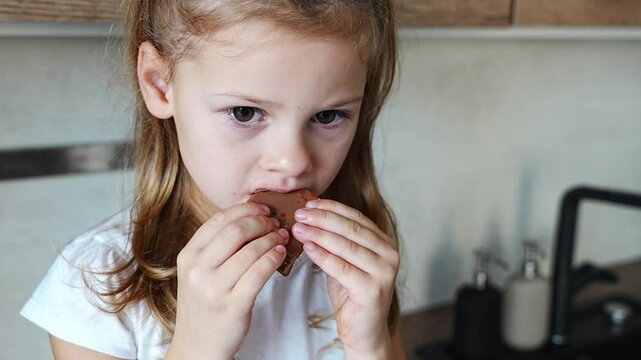 Little girl eating Dubai chocolate with pistachio paste and kataifi dough. Confectionery handmade sweets at home in the kitchen. 