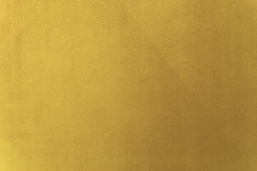 Gold or yellow paint on cement wall texture as background.