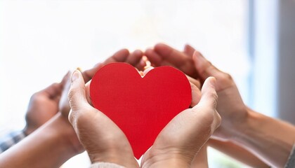 Fototapeta premium Top view of multiethnic people hands holding red paper heart symbol. Group of people standing in circle, promoting unity, love and support for World Organ Donation Day. Charity and altruism