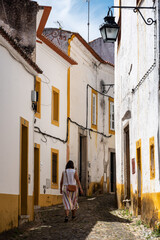 Obraz premium A woman walking through the picturesque Freiria de Cima alley in the medieval city center of Evora