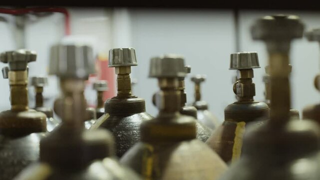 Many metal gas cylinders with valves are in the warehouse and production.