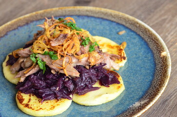 The deep purple of the red cabbage contrasts with the crispy, golden-brown potato pancakes and the succulent, slow-cooked duck meat