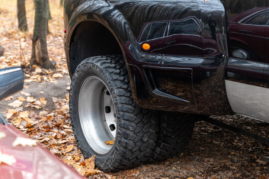 Close-up detail bottom pov view of dual twin offroad performance wheel of super heavy duty pickup truck car at autumn forest countryside driveway. Autumn weather woods offroad vehicle drive