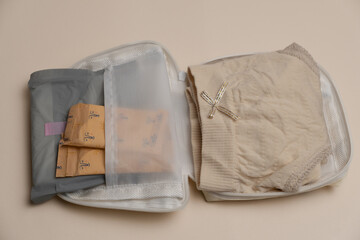 Compact pouch with sanitary products and beige underwear inside