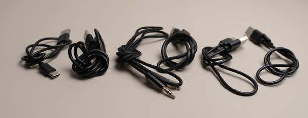 Various black cables and connectors neatly laid out on a beige background, showcasing different types of USB and audio cables