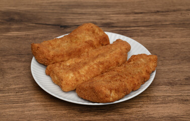 Breaded fried fish on a plate, appetizing pieces in breadcrumbs