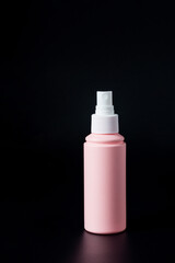 Cosmetic pink bottle. Womens cosmetic accessory for makeup on black background.
