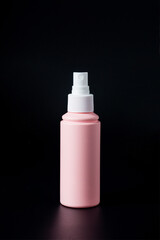Cosmetic pink bottle. Womens cosmetic accessory for makeup on black background.