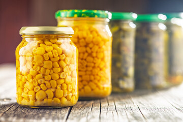 Canned sweet corn in jar on wooden table.