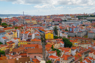 Obraz premium Suspension bridge Ponte 25 de Abril in Lisbon, Portugal. View of colourful facades and The 25th April Bridge over river Tajo. Travel summer photography.