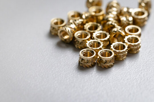Close up of a pile of M4 metric brass inserts for 3d prints. and injection molded parts.