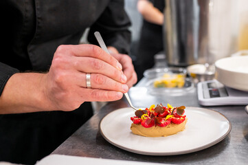 Close-up of a chef’s hands meticulously garnishing a dessert with edible flowers, showcasing culinary artistry and attention to detail. Perfect for culinary, food presentation, and gourmet themes.