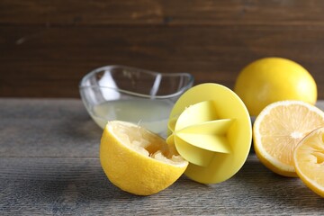 Plastic juicer and fresh lemons on grey wooden table, closeup
