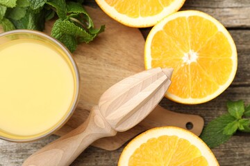 Juicer and fresh oranges on wooden table, flat lay