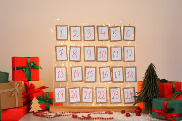 Handmade advent calendar, gifts and decor on table near light wall. Christmas tradition