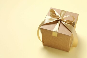 Beautiful gift box tied with golden bow on color background 