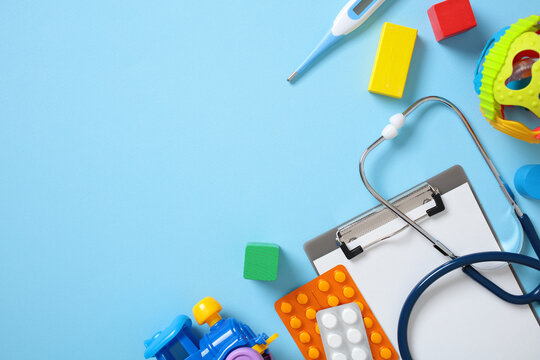 Pediatric care concept. Flat lay composition with playful toys and healthcare items on blue background