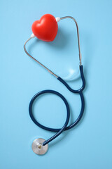 Red heart and stethoscope on blue background. Heart health and care concept.