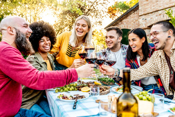 Group of friends toasting red wine glasses at barbecue backyard home party happy hour- Multiracial people having fun at bbq dinner outdoor in garden restaurant - Friendship, youth and party concept