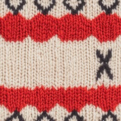 A close-up view of a knitted fabric featuring intricate patterns in red and black on a cream background.