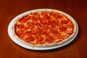 Pepperoni pizza on a plate on a wooden background