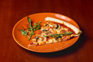 Slice of Italian pizza with mushrooms and bacon on a plate on a wooden background