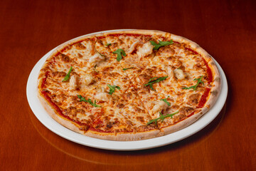 Italian pizza with shrimps on a plate on a wooden background