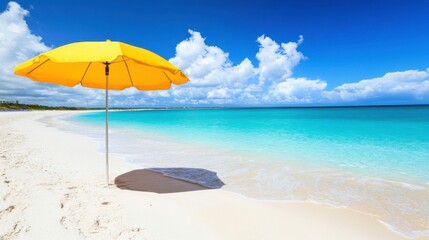 Fototapeta premium Sunny beach with a yellow umbrella by the water.