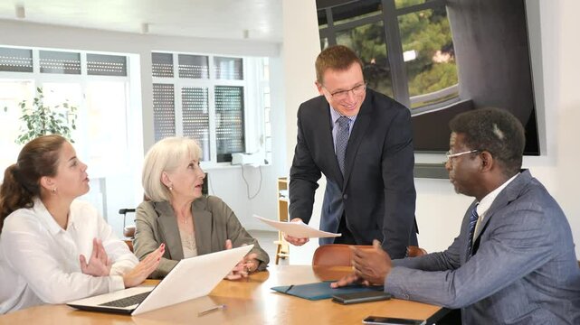 Positive partner men and women discussing a problem sitting around table in meeting room