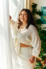 A joyful plus size woman basks in sunlight streaming through her window, radiating positivity.