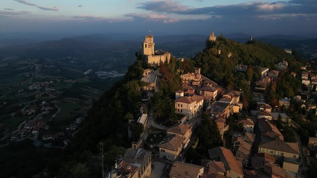 Drone fly close to the tower of San Marino old medieval city in autonomous republic inside Italy , aerial footage at sunset