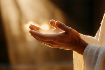 Open hand reaching towards light, symbolizing peace and spirituality. Close-up with warm, soft lighting