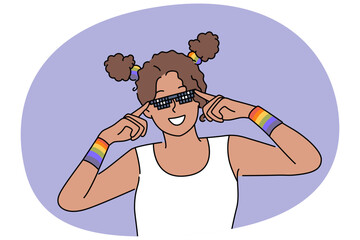 Fototapeta premium Woman with LGBT bracelets adjusts sunglasses and smiles, drawing attention to problems of LGBTq community. African American girl fight against discrimination against lesbian and LGBT activists