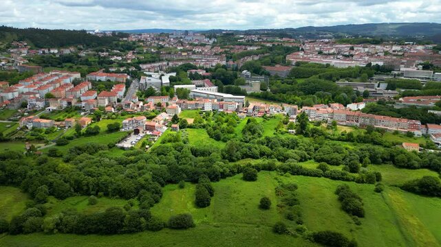 Santiago de Compostela, aerial view. Panoramic view from Monte de Deus. Green landscape, tipically for this region. Cloudy sky. North part of the city. Drone slowly descending. View of all region.
