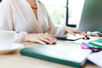 A plus size woman focuses on her work at office surrounded by colorful stationery and a cup.