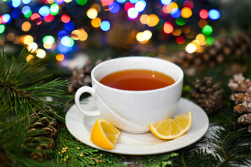 White teacup with lemon wedges, pine cones, and string lights creating a cozy christmas atmosphere